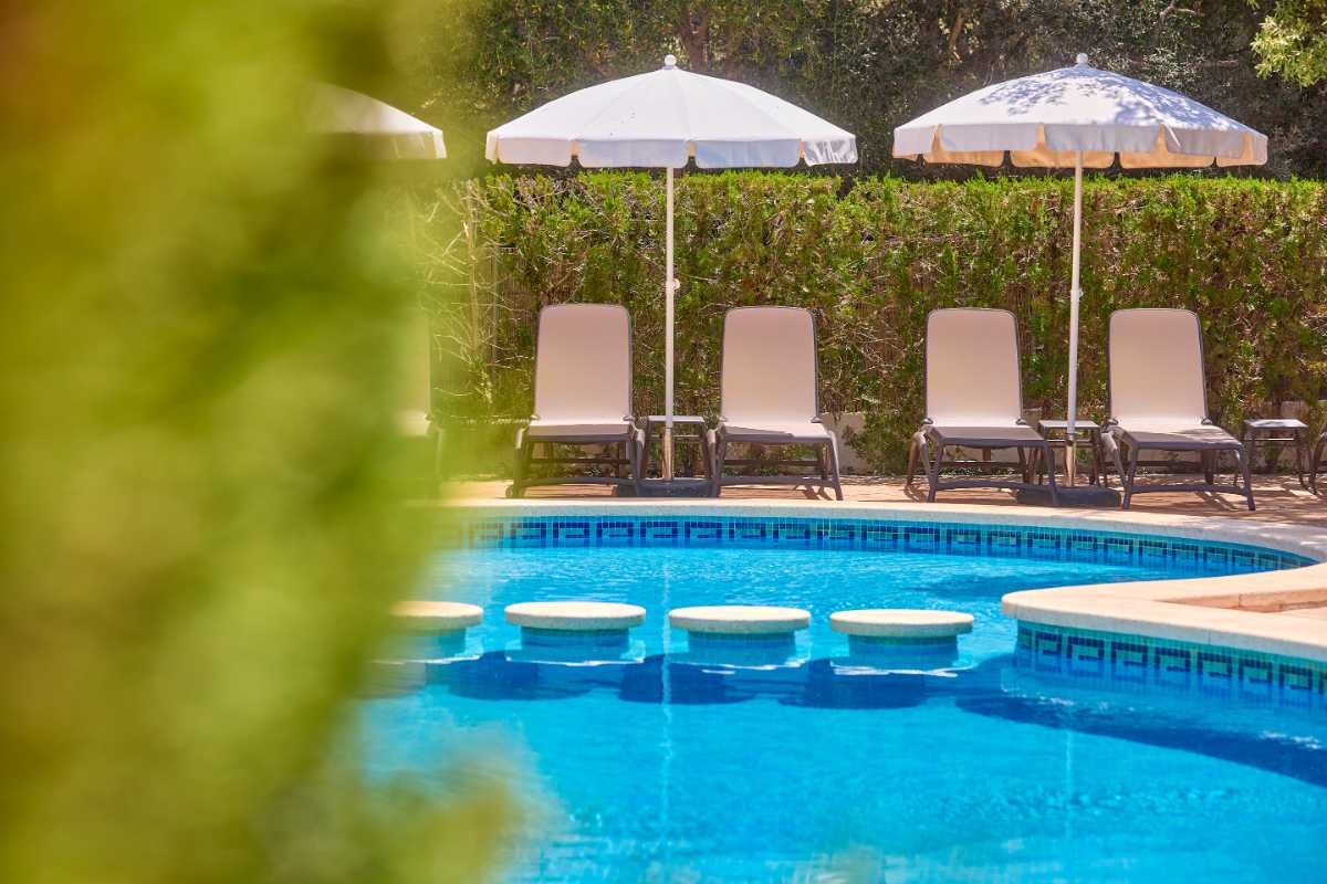tumbonas y sombrillas cerca de la piscina en universal apartamentos Canyamel garden