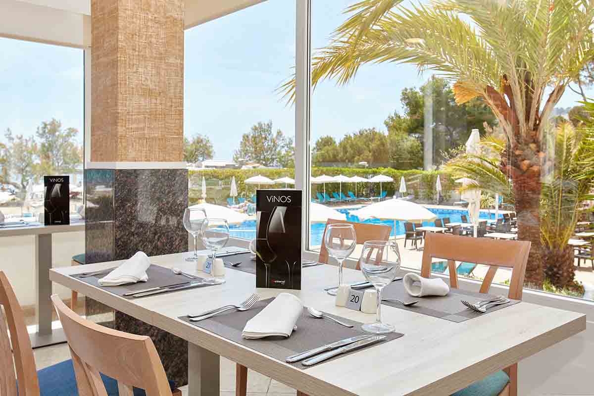 tavoli del ristorante con accesso al giardino con palme all’Universal Hotel Castell Royal